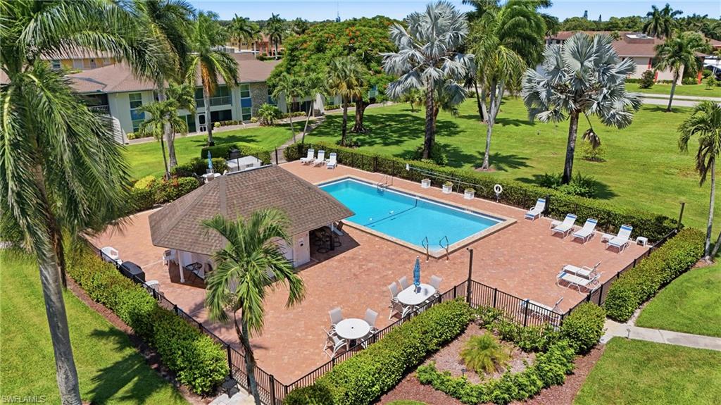 Outdoor swimming pool with a surrounding paver deck, a shaded cabana structure, and an adjacent green space