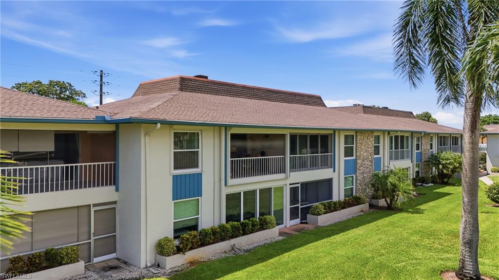 Multi-story building featuring balconies, screened patios, and a well-maintained lawn