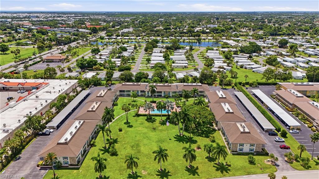 Community setting featuring multiple residential buildings, a central green space, a swimming pool, and covered parking structures