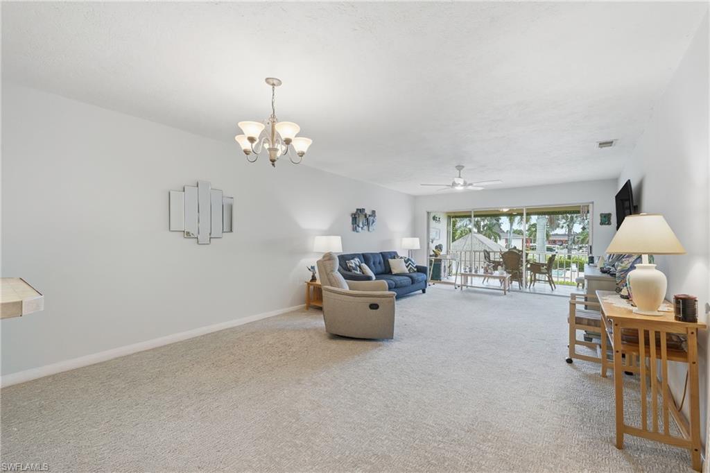 Spacious living area featuring light-toned carpeting and a chandelier