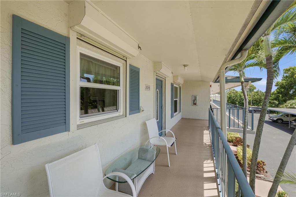 Covered entry porch featuring blue louvered shutters, hurricane shutter, and a blue entry door