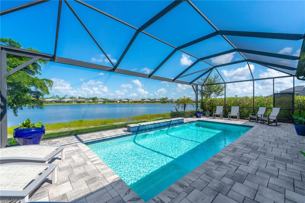 Screened-in outdoor living space featuring a saltwater pool with a water feature, paver patio, and beautiful lake views