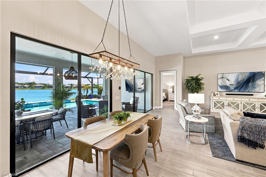 Open-concept living area with tray ceiling, tile  flooring, and expansive sliding glass doors to outdoor living area