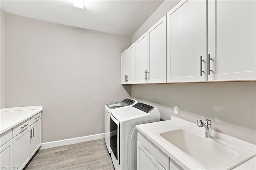 Large laundry area featuring extensive white cabinetry,  a utility sink,  and tile flooring