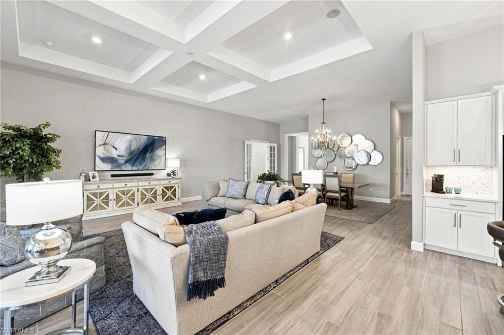 Coffered ceilings with recessed lighting, wood-tile flooring, kitchen with under-cabinet lighting, and a formal dining area with a chandelier