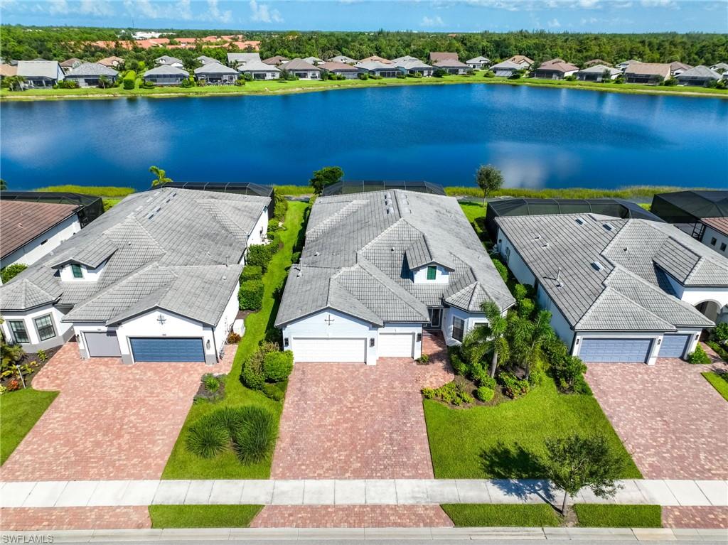 Lakeview property featuring a tile roof, paver driveway, attached 3 car garage, and manicured landscaping