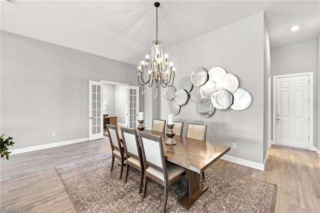 Spacious formal dining area featuring vaulted ceilings, wood-look tile  flooring, and a decorative chandelier