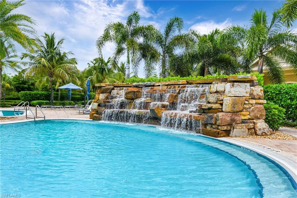Resort-style community pool and spa with a stone waterfall feature and surrounding tropical foliage