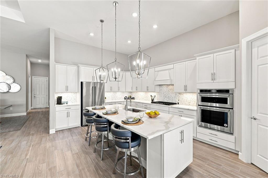 Modern kitchen featuring white cabinetry, quartz countertops, under cabinet lighting and stainless steel appliances