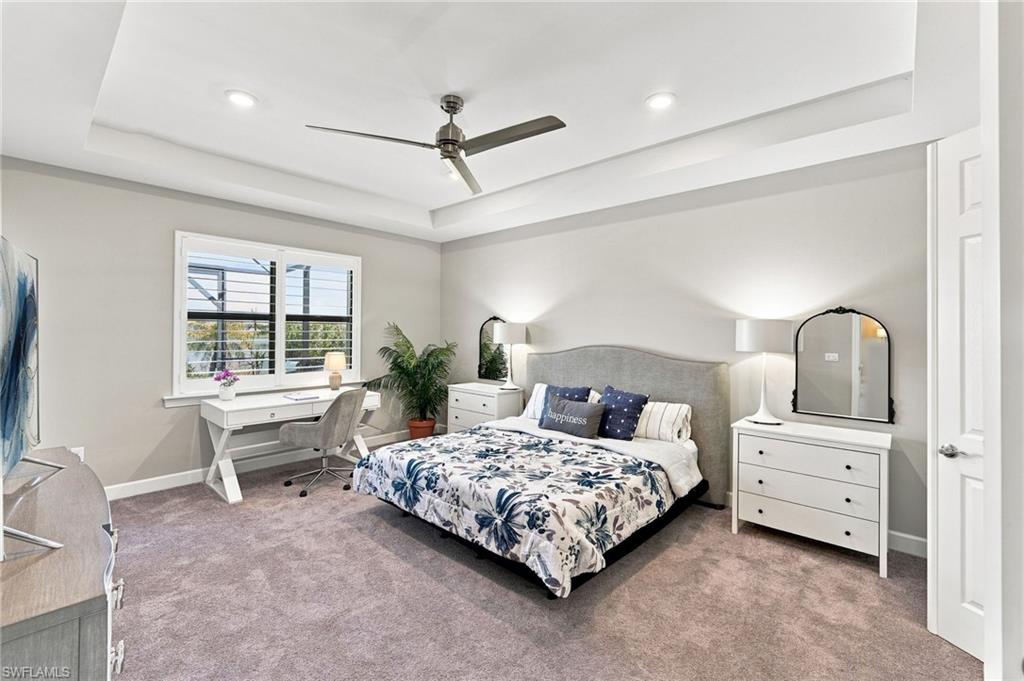 Large primary bedroom with tray ceiling, recessed lighting and a modern ceiling fan