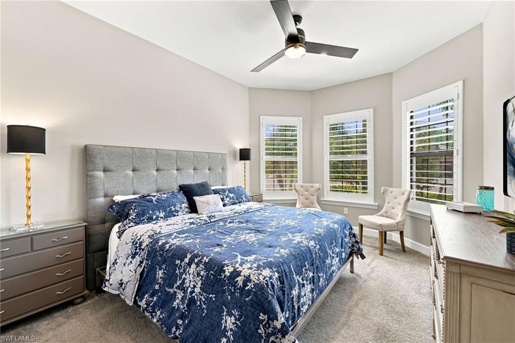 Bedroom 2 with tray ceiling , bay window with shutters, light gray walls, and carpet flooring