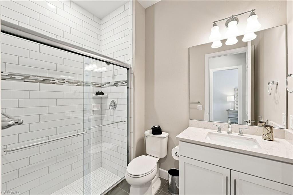 Modern guest  bathroom featuring white subway tile shower surround with glass enclosure, white cabinetry and quartz countertop