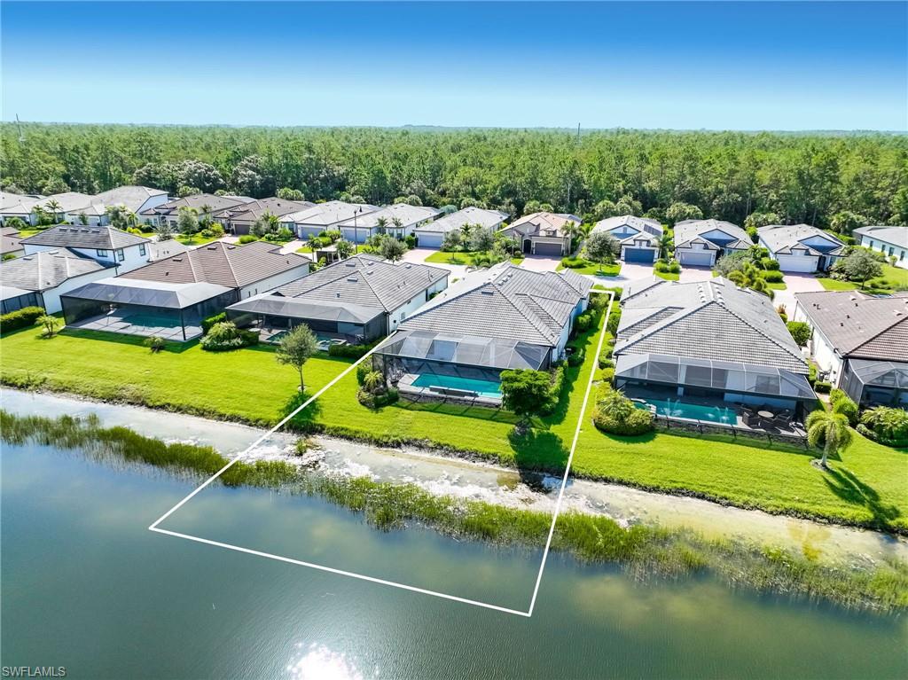 Oversized  waterfront property featuring a screened-in swimming pool and a manicured lawn