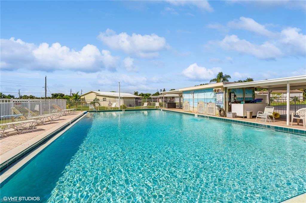 Expansive swimming pool with a tiled perimeter, surrounding paved deck, and adjacent covered poolside structure