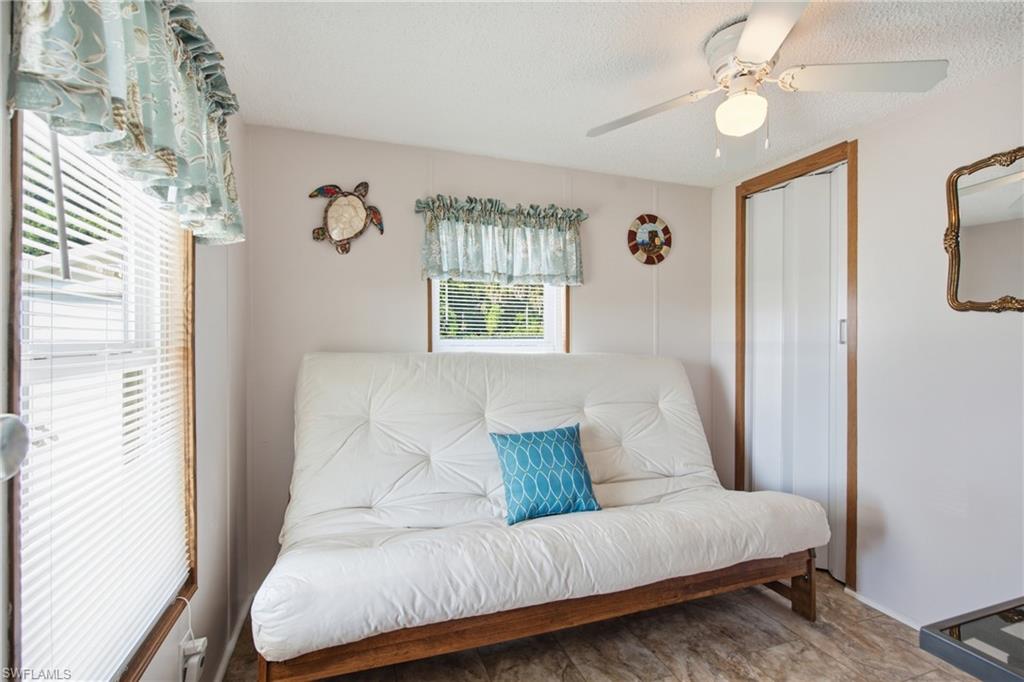 Room featuring multiple windows, a ceiling fan with integrated lighting, and wood-finish flooring