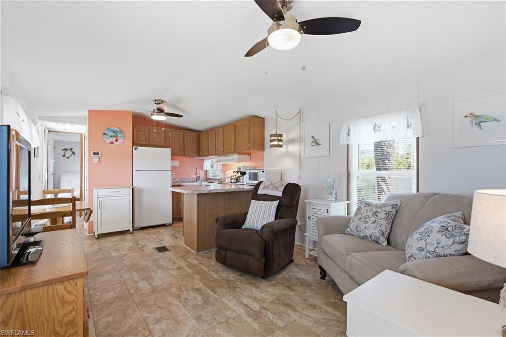 Kitchen and living area featuring wood-finish flooring, ceiling fans, wood cabinetry, and a kitchen island with a countertop