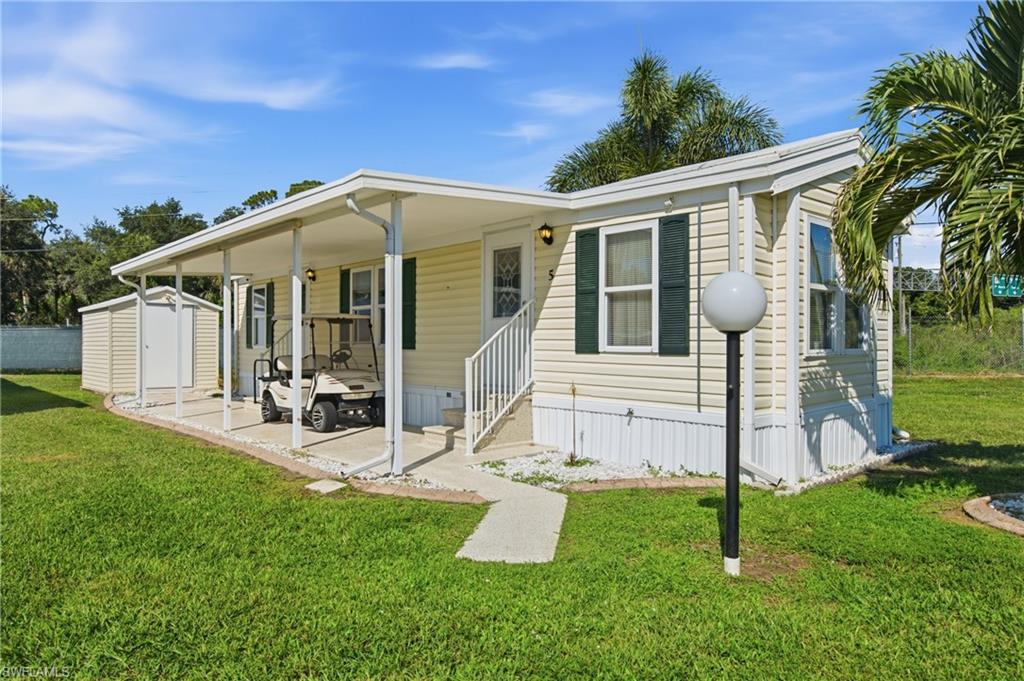 Open Porch with concrete slab, exterior storage shed, siding exterior, shutters, and manicured lawn