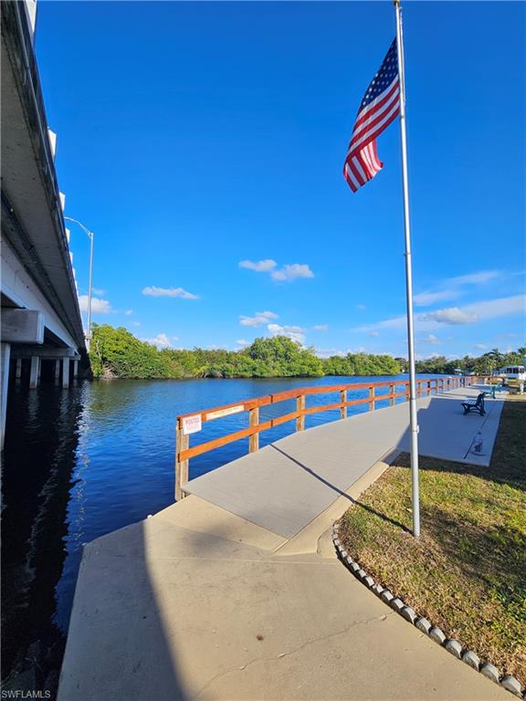 Concrete waterfront walkway with wood-finish railing and adjacent grass area