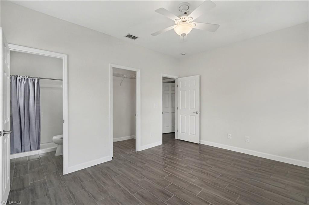Wood-finish tile flooring, ceiling fan, white paneled doors, and an en-suite bathroom with a shower-tub combination