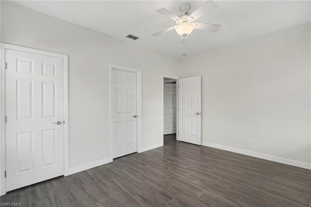 Wood-finish plank flooring, crisp white walls, white trim, and a ceiling fan with integrated lighting