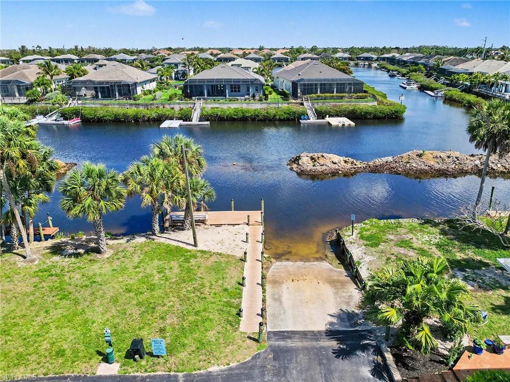 Waterfront property featuring a private boat ramp, dock, and mature palm trees