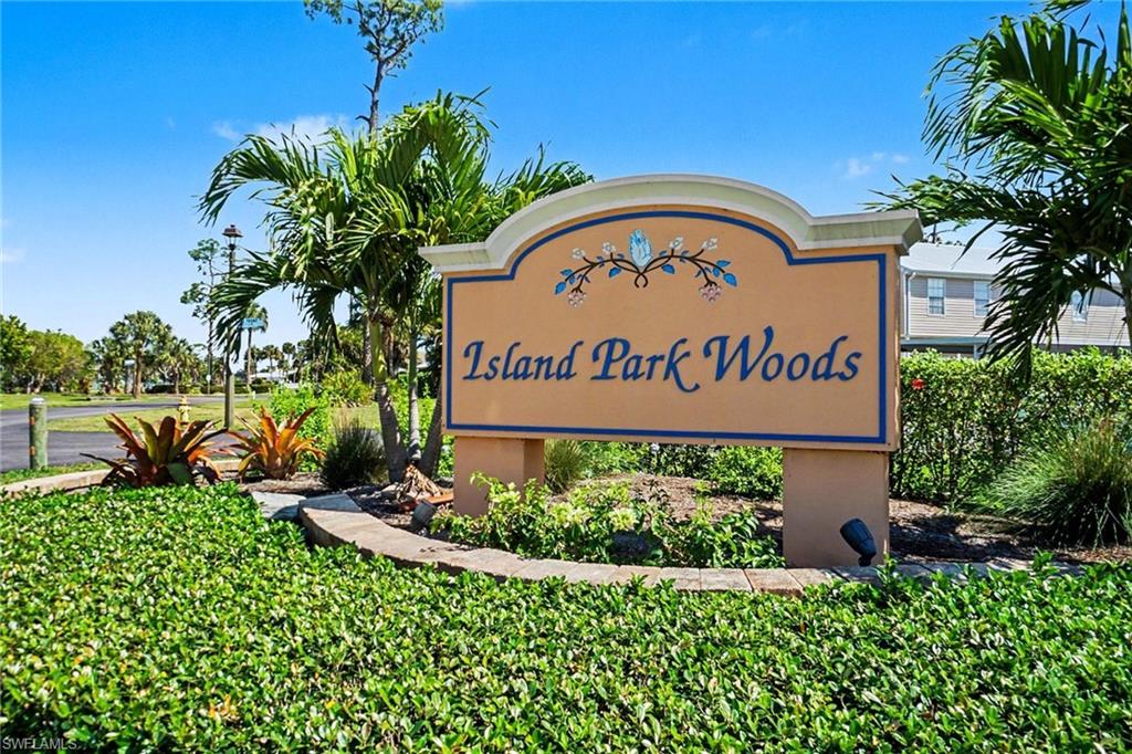 Entryway signage featuring decorative trim and planted tropical vegetation