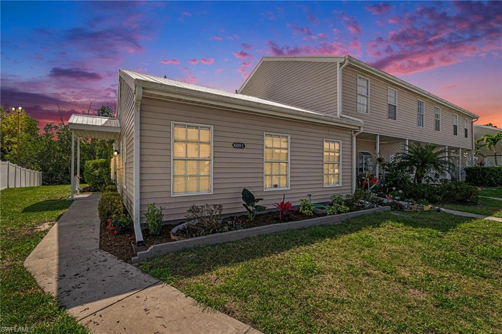 Siding exterior with multiple windows, a concrete walkway, and landscaped garden beds
