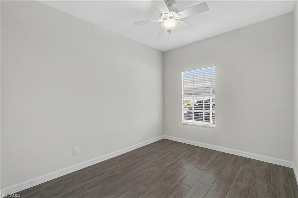 Neutral wall color, wood-finish tile flooring, and a ceiling fan with integrated lighting