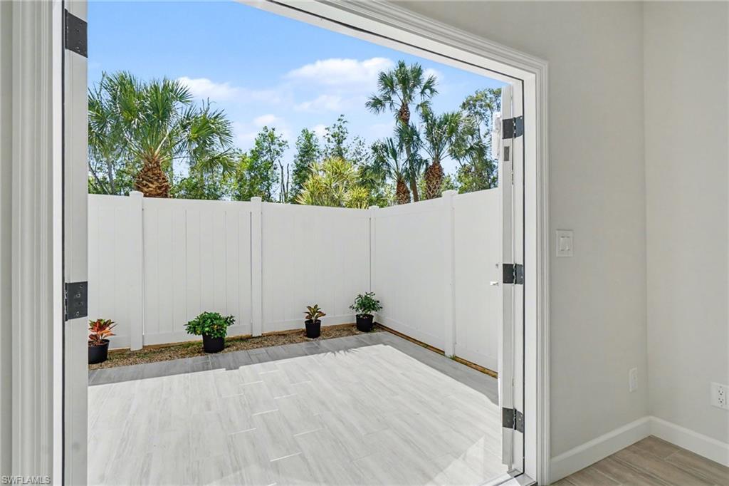 Private outdoor patio featuring light-toned plank-style flooring and a white privacy fence