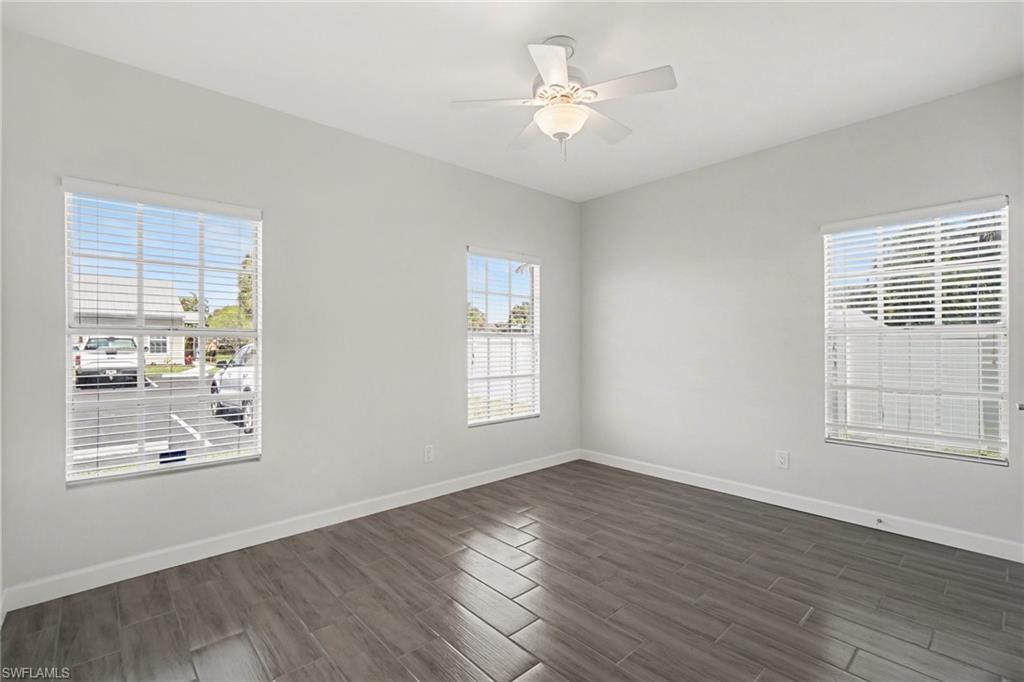 Wood-finish tile flooring throughout, multiple windows with blinds, and an overhead ceiling fan with integrated lighting