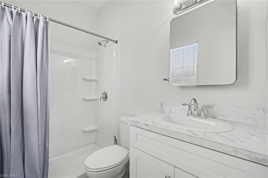 White vanity with a drop-in sink, chrome fixtures, and a stone-finish countertop