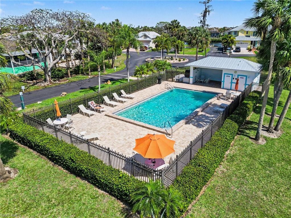 Fenced outdoor pool area featuring a rectangular pool, paver deck, and adjacent pool house