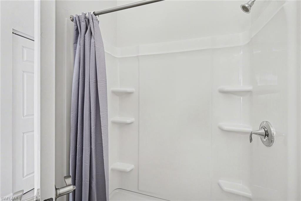 White shower surround with integrated shelving and chrome fixtures