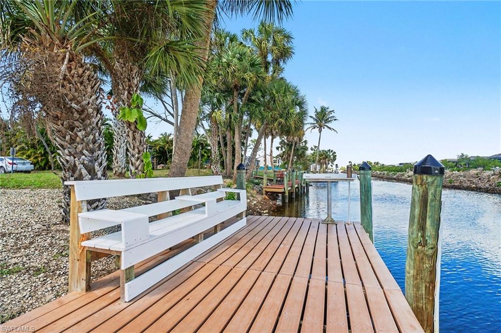 Wood dock extending over a waterway, featuring a white built-in bench