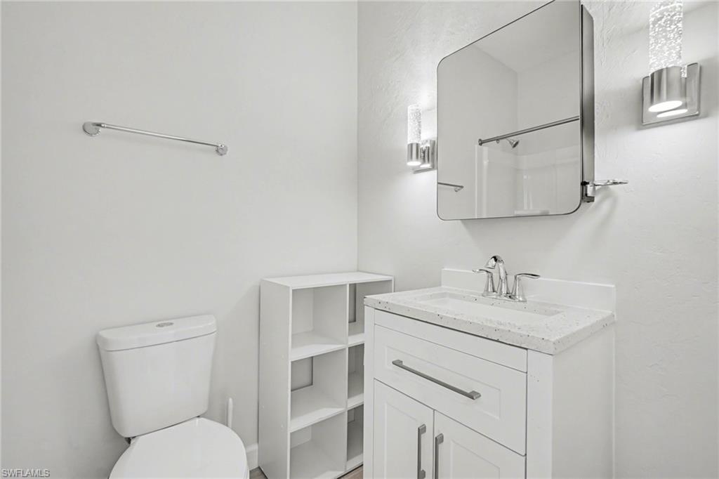 White vanity with stone-finish countertop and integrated sink, chrome faucet, and storage cabinetry