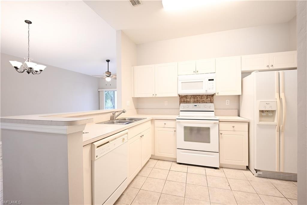 Kitchen featuring white cabinetry, a double basin stainless steel sink, a tile backsplash, and a breakfast bar