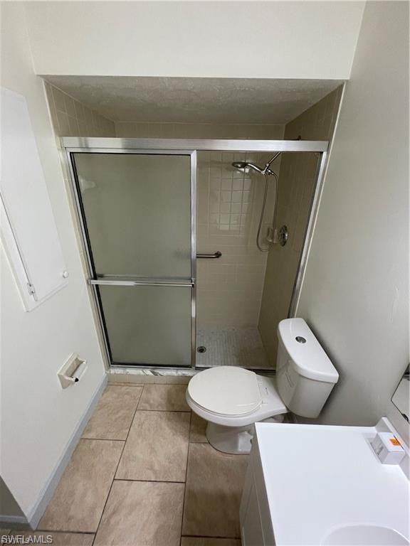 Shower enclosure with sliding frosted glass doors, tiled shower surround, and a wall-mounted shower head