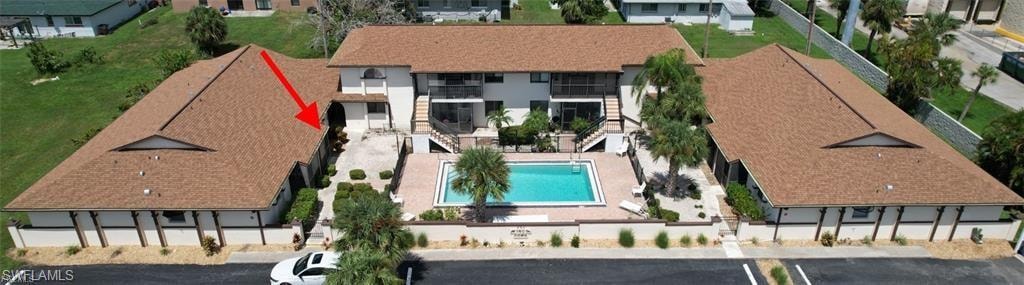 Community with a central swimming pool, paved pool deck, and mature landscaping