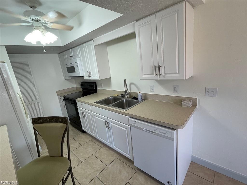 Kitchen featuring white cabinetry, light-toned countertops, a stainless steel double basin sink, and tile flooring