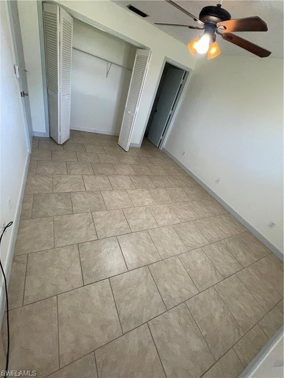 Neutral-toned tile flooring, built-in closet with louvered bifold doors, and a ceiling fan with integrated lighting