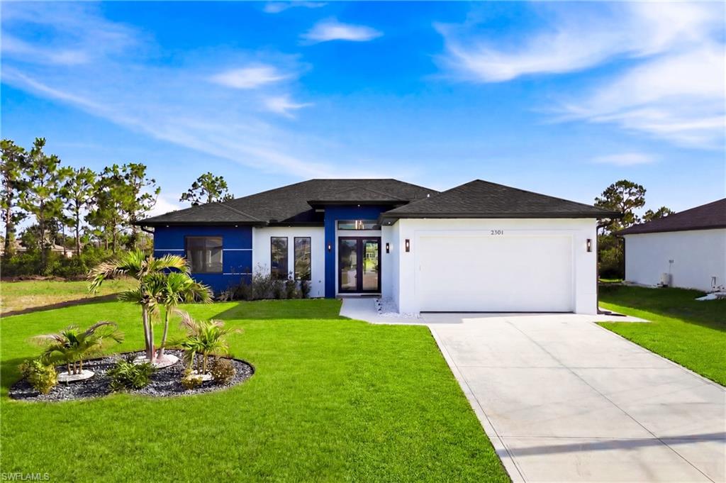 Contemporary architectural design featuring a two-car garage, concrete driveway, and a manicured lawn