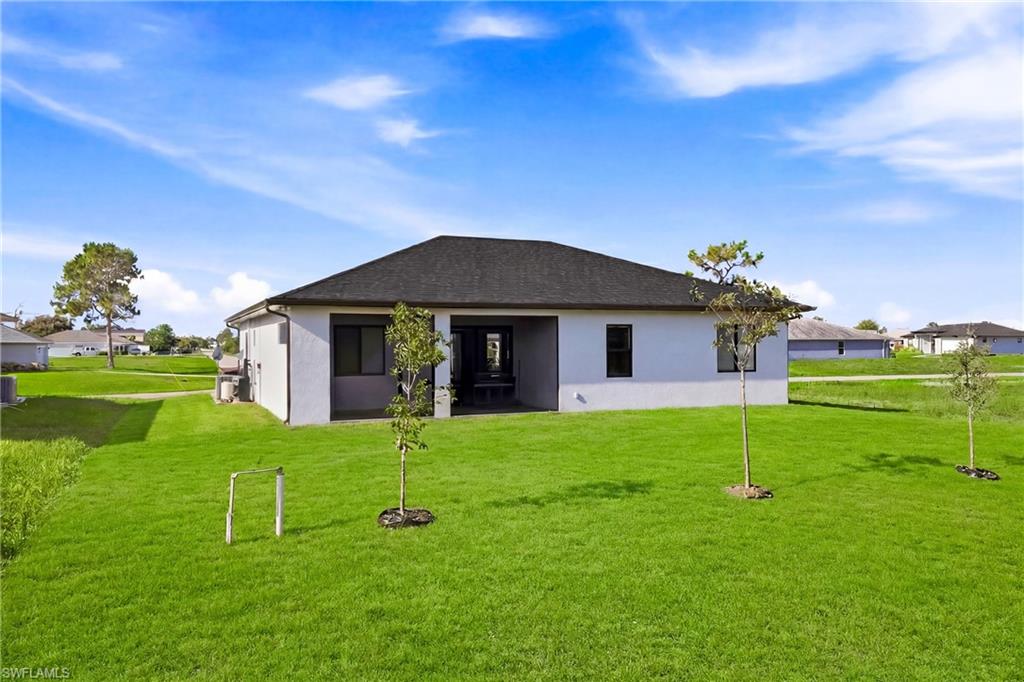 Expansive grassy yard with a covered patio and a dark shingled roof