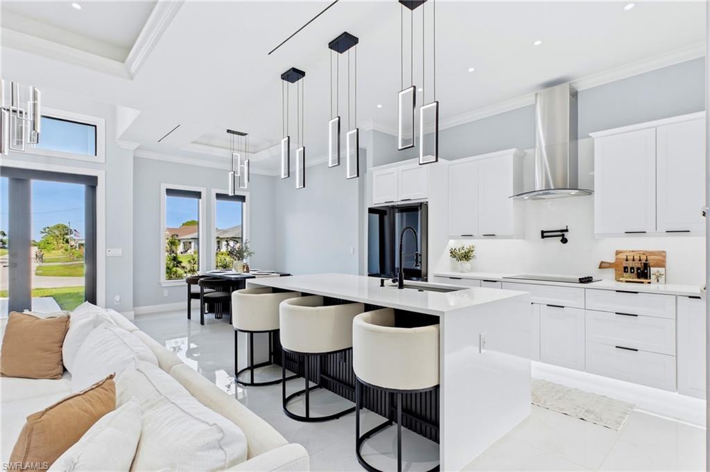 Gourmet kitchen with stainless steel appliances, custom cabinetry, a large island with seating, and contemporary pendant lighting