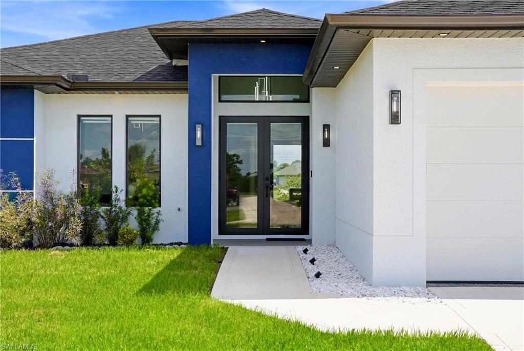 Exterior featuring a dual-tone facade, double entry doors, contemporary wall sconces, a two-car garage, and a concrete walkway