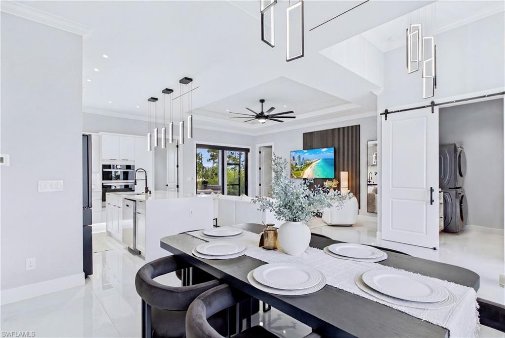 Open-concept interior featuring a modern kitchen with integrated appliances, a dining area with contemporary pendant lighting, and a living space with a ceiling fan