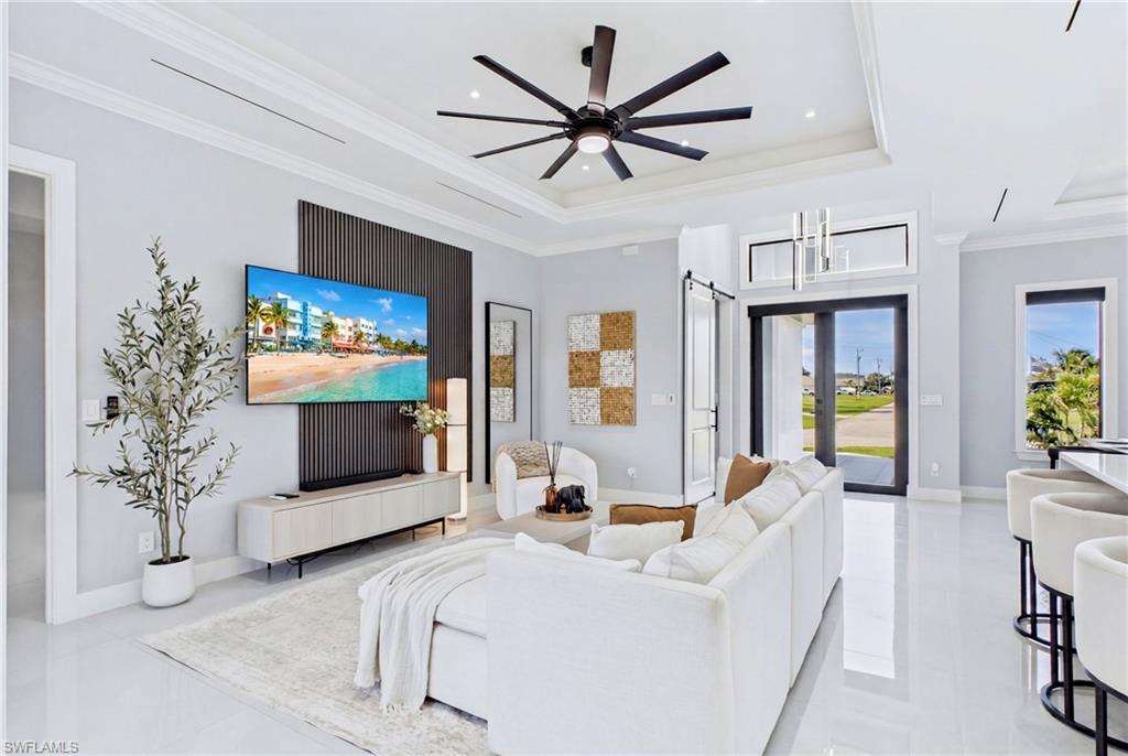 Recessed lighting, ceiling fan, tray ceiling, sliding glass doors, and white tile flooring
