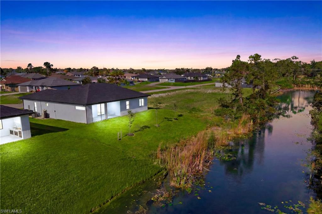 Expansive green lawn, mature trees, and a tranquil pond with natural vegetation
