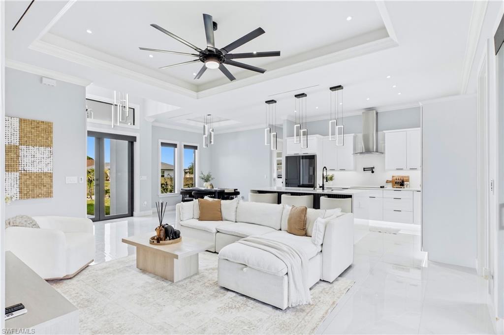 Open-concept living space featuring high ceilings, contemporary lighting fixtures, white cabinetry, and stainless steel appliances