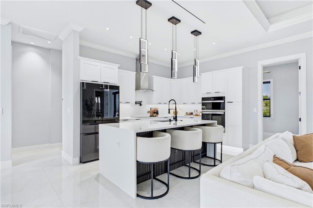 Kitchen featuring white cabinetry, a central island with integrated seating, recessed lighting, and stainless steel appliances