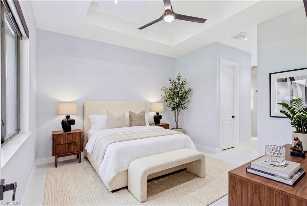 Recessed ceiling with an integrated ceiling fan and lighting, large windows, wood-finish flooring, and a two-panel interior door